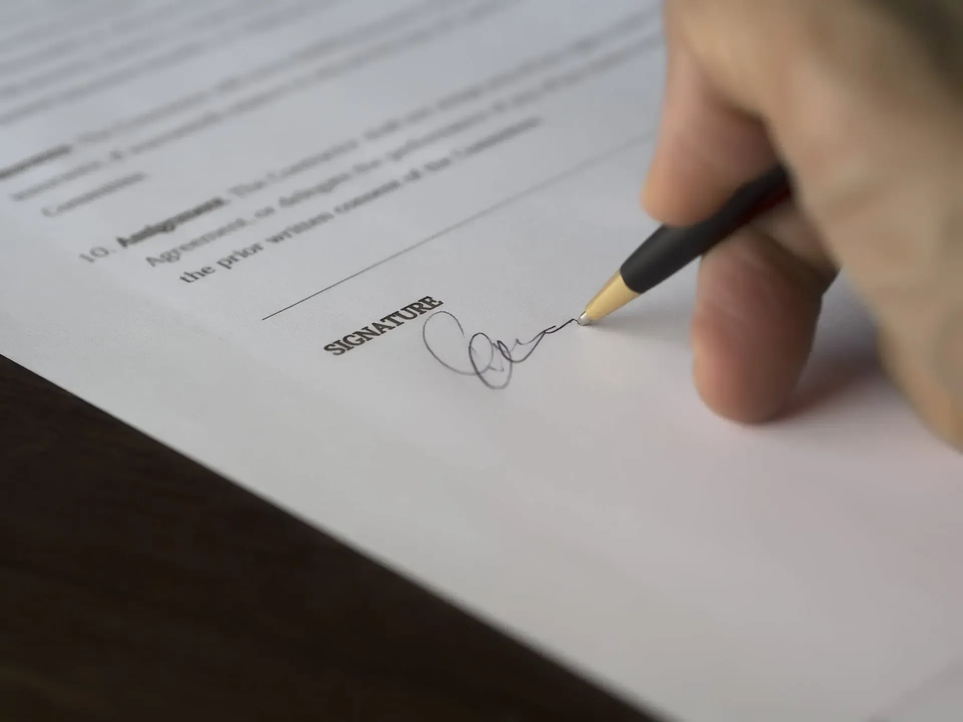 A person signing a document with a section labeled "SIGNATURE."